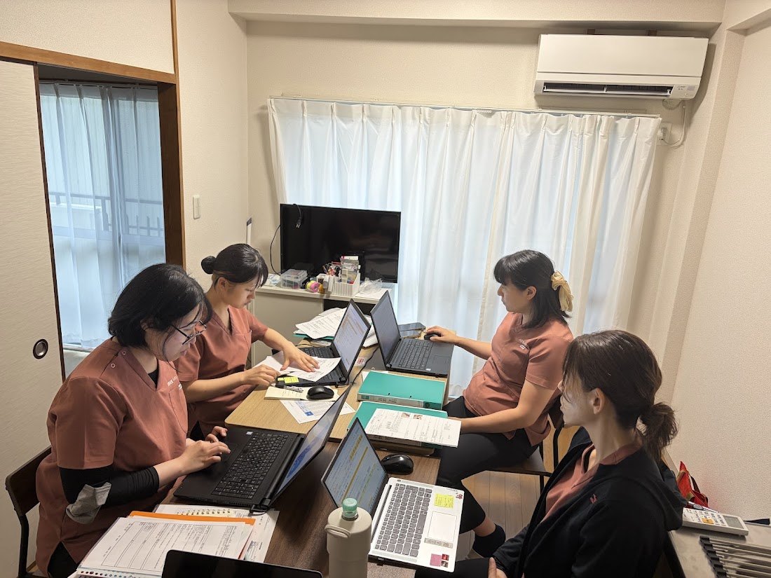 WaKoの事務所で4人のスタッフが記録・報告をしながら情報共有する様子
